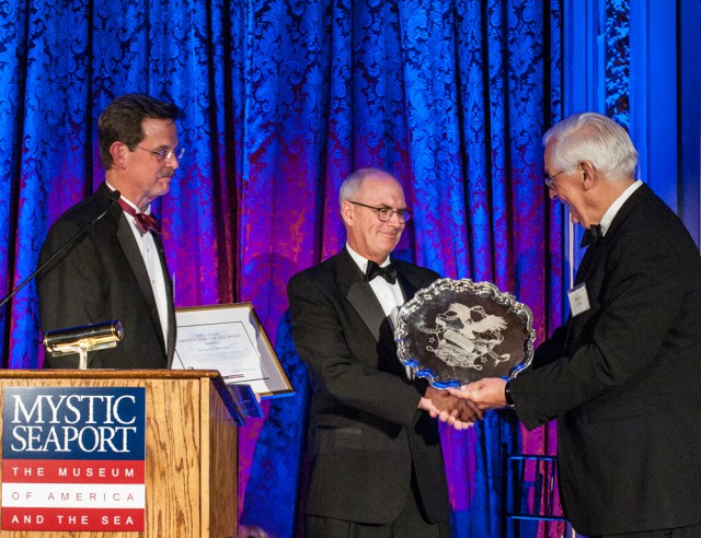 Mystic Seaport Board of Trustees Chairman Barclay Collins (right) presents Nathaniel Philbrick (center) with the 2015 America and the Sea Award in New York City on October 14, 2015. Standing behind the podium is Museum President Steve White.